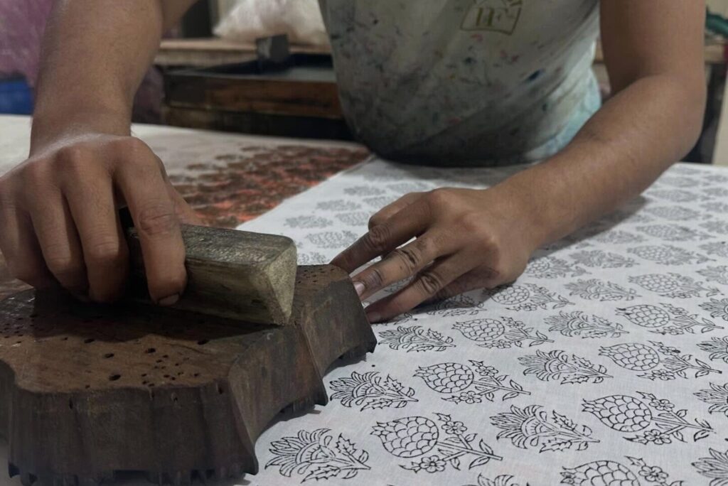インドの職人が木版を一つひとつ手で押して柄を作る、伝統的なブロックプリント(木版摺り)の様子。